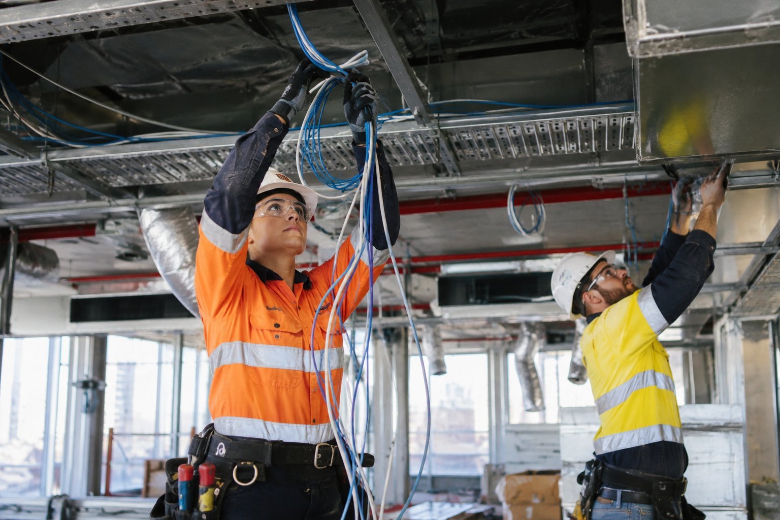 Tradespeople installing ceiling services and cabling in a Sydney office fitout
